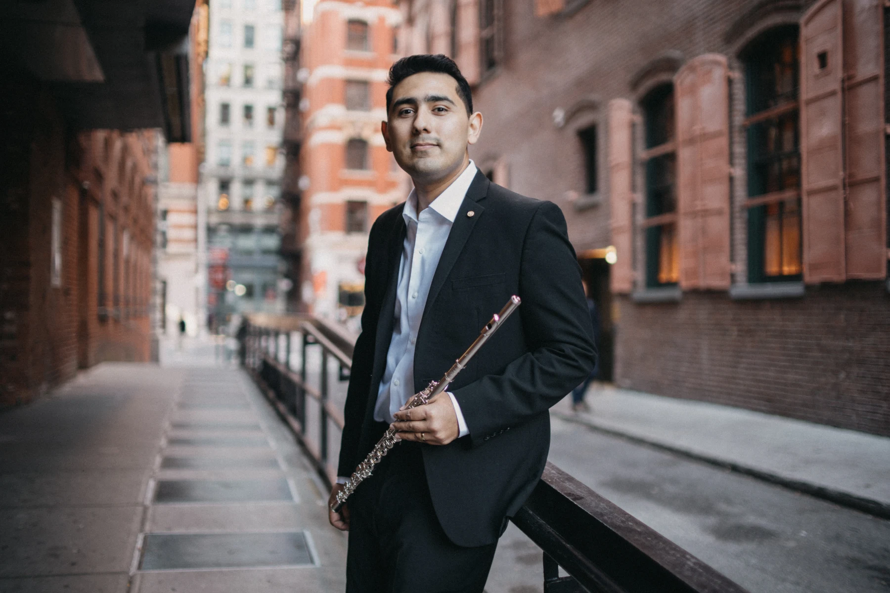 Saqtiel with his flute on a brick-lined New York street